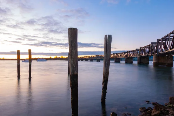 新西兰图兰加历史性的铁路桥和日出时港口的老锚泊站 — 图库照片