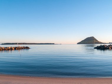 Gün doğumunda Tauranga limanı boyunca uzanan Maunganui Dağı güzel mavi deniz ve gökyüzü ile birlikte..