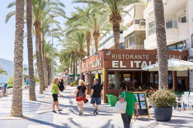 Calpe İspanya - 24 Ağustos 2016; Turist kıyı kasabasındaki tipik Akdeniz sokağı halkı sokak boyunca palmiye ağaçlarıyla kaplı eski restoranlar