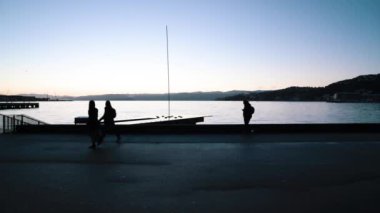 Wellington Yeni Zelanda 'da şafak vakti rıhtımdan geçen insanların siluetleri..