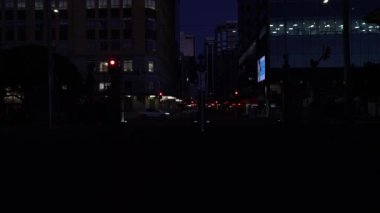 Şehir merkezinin arka planında, şafaktan önce karanlık bir gecede sokağın ortasından geçen arabalarla karanlık arka plan videolarını aydınlatıyorlar..