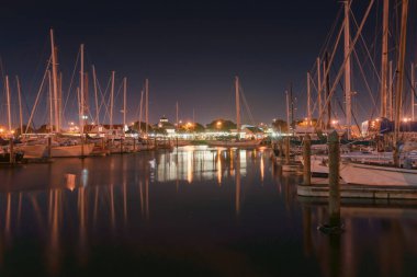 Whangarei Havzası marinası... İskele parmakları ve tekneler arasındaki sakin suda yansımalarla....