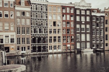 Amsterdam Hollanda - 17 Ağustos 2017; Damrak 'taki renkli ikonik apartmanlarda eski dünya fotoğraf efektleri mimari, gable ve pencere.