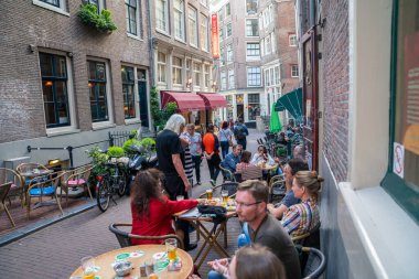Amsterdam Hollanda - 17 Ağustos 2017; İnsanlar Avrupa 'nın dar sokaklarındaki açık hava masalarında sosyalleşiyor, yiyor, içiyor