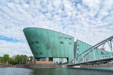 AMSTERDAM, HOLLAND - 17 AĞUSTUSTOS; NEMO Büyük yeşil renkli gemi, 17 Ağustos 2017 'de Amsterdam, Hollanda' nın girişine giden yaya köprüsü kanalı ile bilim müzesi inşa ediyor..