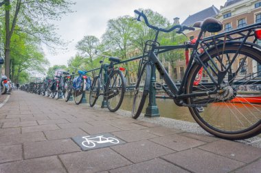 Amsterdam, Hollanda 'da uzun bisiklet kuyrukları dizilip kanal kenarına kilitlenmiş ve bisiklet grafikleri çizilmiş..