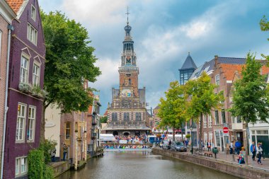 Alkmaar Hollanda - 18 Ağustos 2012; Kanalın sonundaki işlek Picturesque kasabası, ve peynir pazarı, tarihi anıtlar ve peynir ile ünlü noktalar girişin yanında turist kalabalığı, kanal teknesinde yüzüyor ve sokakta yürüyor