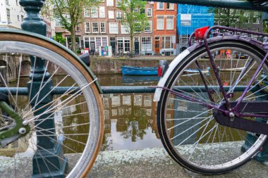 Amsterdam Hollanda - 19 Ağustos 2017; Kanal boyunca demirlemiş Capital Value adlı mavi tekne bisiklet tekerlekleri arasında ön planda çözülmüş olarak görülüyor