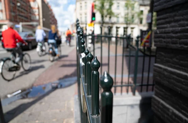 Defocussed blurry street background image with wrought iron balustrade in city of Amsterdam Netherlands and cyclists passing.