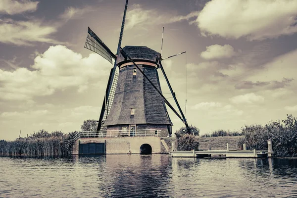 Traditional Dutch windmill in old-fashioned effect with dramatic cloudy sky, Kinderdijk, Netherlands.