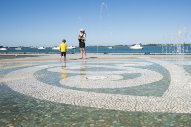 Küçük çocuk ve annesi su özelliği Tauranga, Yeni Zelanda, tabanı etrafında etnik tasarımı yürü.