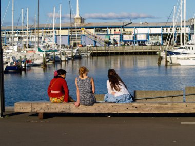 İskele kenarında oturan üç gençler