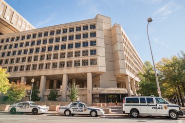 Police vehicles parked in street outside FBI Building in Pennsylvania Avenue Washington DC. clipart
