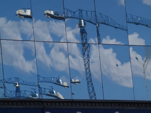 Glazen buitenwand weerspiegelt kraan — Stockfoto