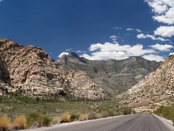 Camino recto plano que se extiende en colinas distantes en el desierto de Nevada . — Foto de Stock