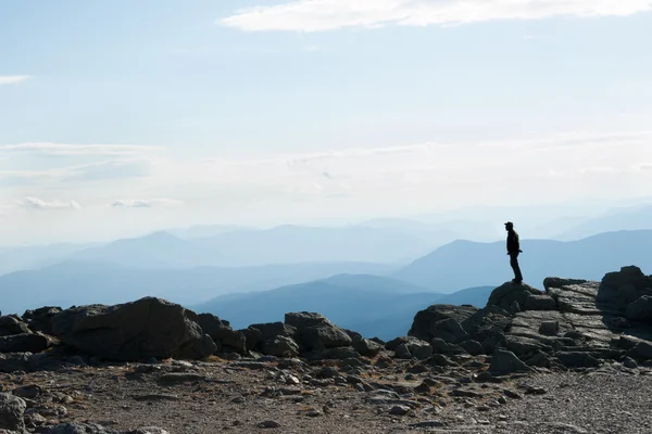 On mountain top, silhouette of man, unrecognisable stands on rock looking into the view. — Stock Photo, Image