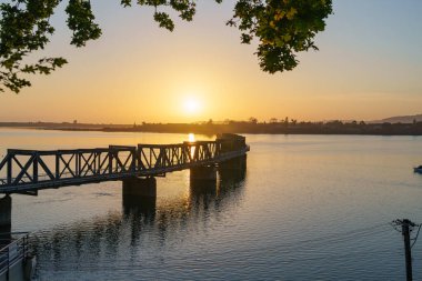 Güneş, Tauranga limanı ve tarihi demiryolu köprüsünden yükseliyor sakin bir sabahta Elizabeth Caddesi 'nin doğusundan şehrin merkezine bakıyor.