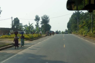 Nyungwe Rwanda - 6 Eylül 2025; Köydeki üçüncü dünya ülkesinin zorlu yaşamında insanlar kafalarında sepetlerle otoyolda yürüyorlar.