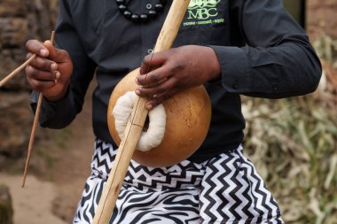 Gasura Rwanda - Eylül 2025; Otantik Afrika köyü, yayla oynayan tek telli Rwandan müzik enstrümanıyla hayatta ve el ele tutuşan canlı insanlar