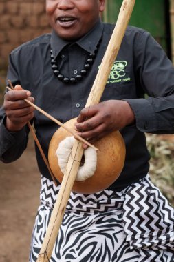 Gasura Rwanda - Eylül 2025; Otantik Afrika köyü, yayla oynayan tek telli Rwandan müzik enstrümanıyla hayatta ve el ele tutuşan canlı insanlar .