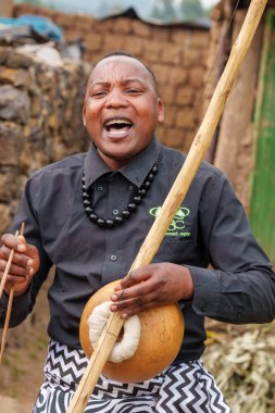 Gasura Rwanda - 8 Eylül 2025; Köy hayatı ve turizm ile uğraşan otantik siyahi Afrikalı insanlar mutlu bir enstrüman çalıyor ve gülüyorlar.