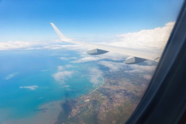 Mavi gökyüzü ve beyaz bulut arkaplan görüntüsünün altında beyaz kanat ve kıyı şeridi var..