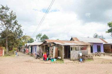 Arusha Tanzanya - 10 Eylül 2025; Sokak ve köy halkı, gelişmekte olan bir ülkenin kırsal kesimindeki yol kenarındaki pazar tezgahlarından ve harap evlerden günlük işlerini yapıyorlar..