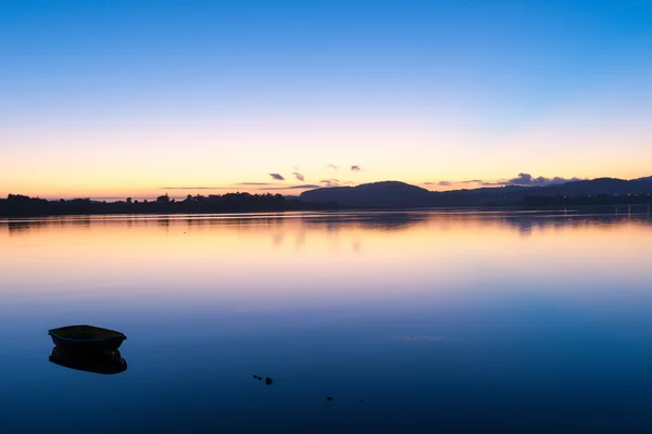 Salida del sol sobre el cielo azul de la bahía transiciones a rosa y naranja desde arriba del horizonte y sobre el agua tranquila . — Foto de Stock
