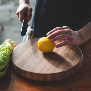 Adam tahtadan bir limon kesiyor. Eller görünür durumda. Yüksek kalite fotoğraf