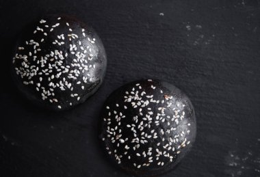 Siyah çörekler ve koyu arkaplanda susam tohumları