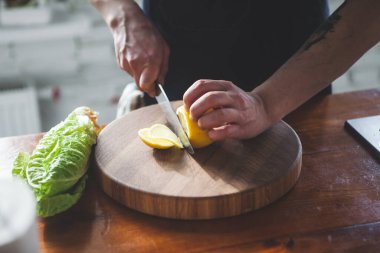 Adam tahtadan bir limon kesiyor. Eller görünür.