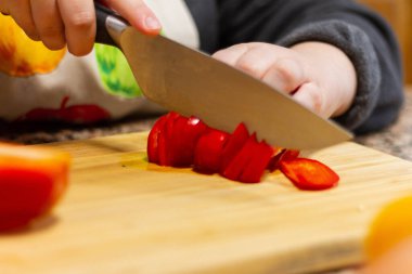 Kırmızı biber kesen bir kızın yakın plan fotoğrafı.