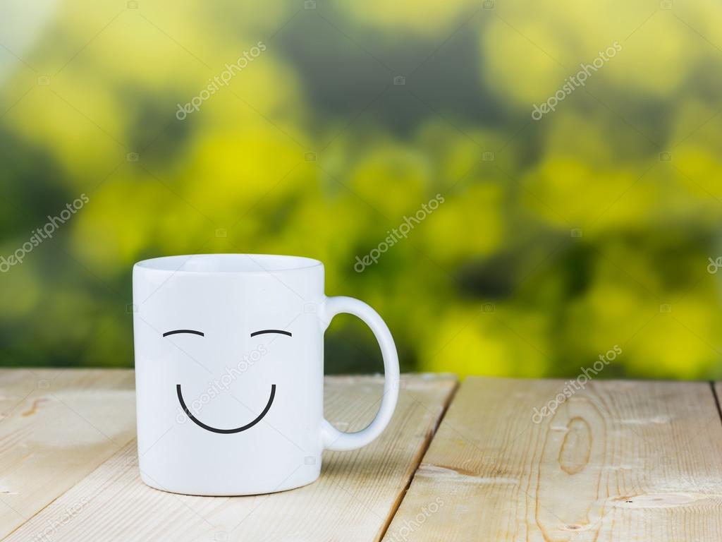 Smiley coffee cup on wood table with green bokeh background ??? Stock