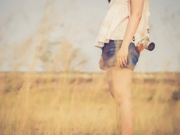 Girl standing in grass field with camera holding, vintage color — Stock Photo, Image