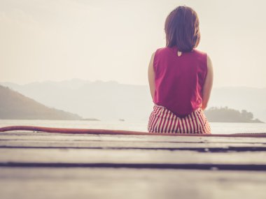 Deniz ve dağ ile ahşap balkonda oturan kız; Filtre vintage