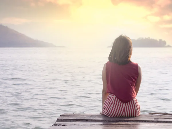 Ragazza seduta su un balcone di legno con luce soffusa; sfondo di viaggio — Foto Stock