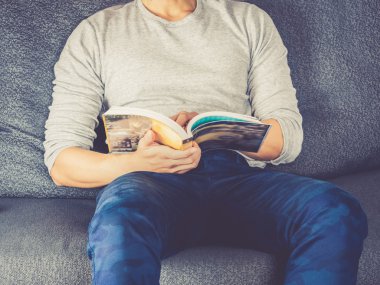 Kanepe okuma kitabı üzerinde yatan genç adam; Retro renk filtresi