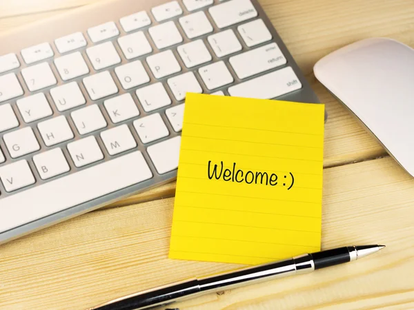 Welcome with smily face on sticky note on work table — Stock Photo, Image