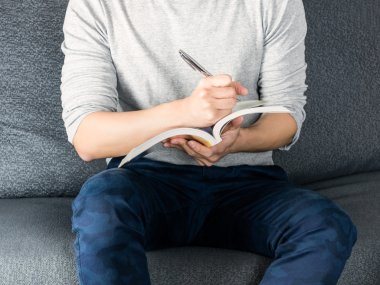 Kitap, kanepeye, çalışma kavramı oturan yazma adam