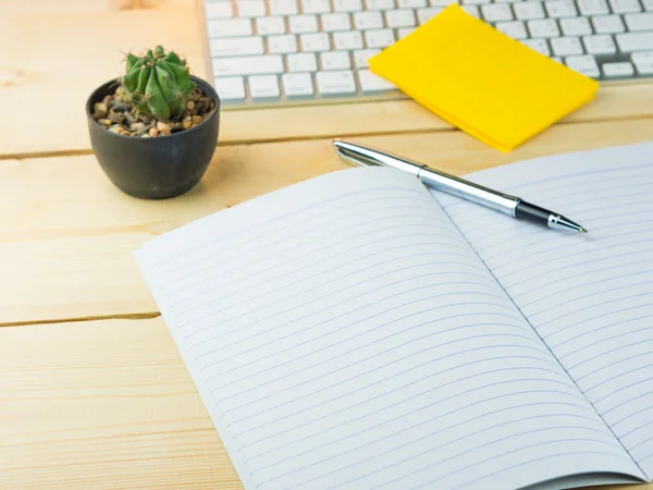 Cuaderno vacío en la mesa de trabajo con cactus, nota adhesiva, pluma, llave —  Fotos de Stock