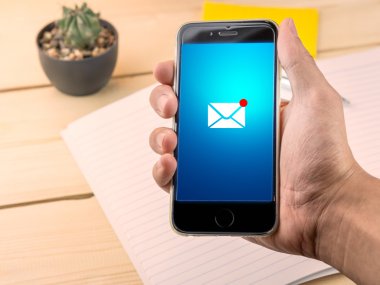 Akıllı telefon yeni iletide; çalışma tablosu üzerinde tutan el