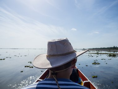 Nehir teknesinde oturan şapkalı adam arka