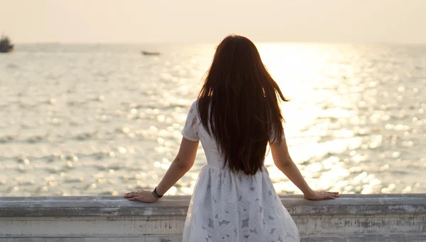 Menina assistindo mar e pôr do sol em uma varanda — Fotografia de Stock