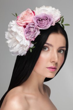 Portre tatlı bir genç güzel model kızın mükemmel parlak deri, günlük çıplak doğal makyaj, pembe dudak parlatıcısı ve başında çiçekler.