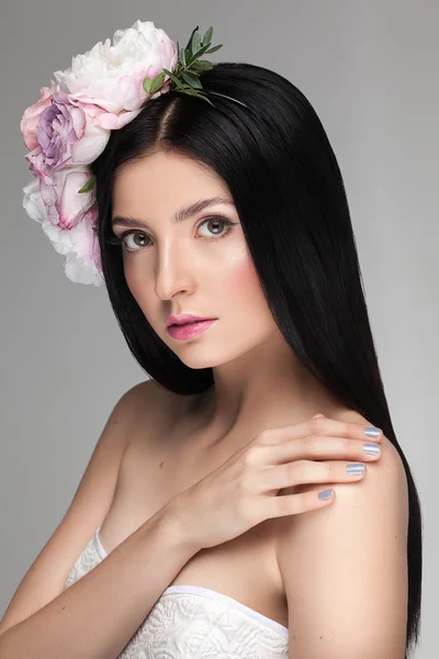 Close-up van het portret van een jonge mooie model meisje met perfecte glimmende huid, dagelijkse naakt natuurlijke make-up, roze lipgloss en bloemen op haar hoofd. — Stockfoto