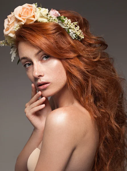 Close-up van het portret van een jonge mooie vrouw met naakt natuurlijke verse dagelijkse make-up en lang krullend rood haar en bloemen op haar hoofd. — Stockfoto