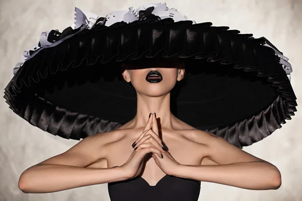 Şehvetli kadın model büyük siyah şapka bir stüdyoda poz.