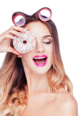 Güzel çekici beyaz kızı tatlı bir pasta alarak saç pembe curlers.