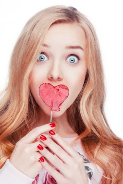 Kırmızı bir lolipop kalp şeklinde alarak studio beyaz arka planda poz mutlu sarışın kız.