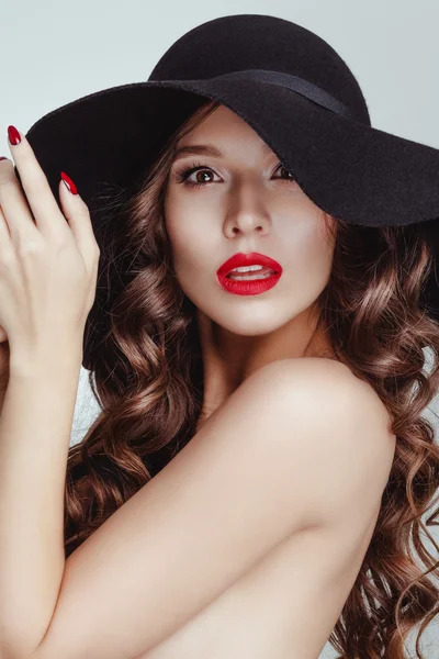 Sinnlich attraktiv charmante brünette Frau trägt einen schwarzen Hut posiert im Studio weißen Hintergrund. — Stockfoto